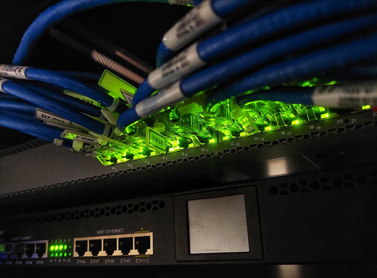 Close-up of network switch with connected Ethernet cables and glowing green LED indicators