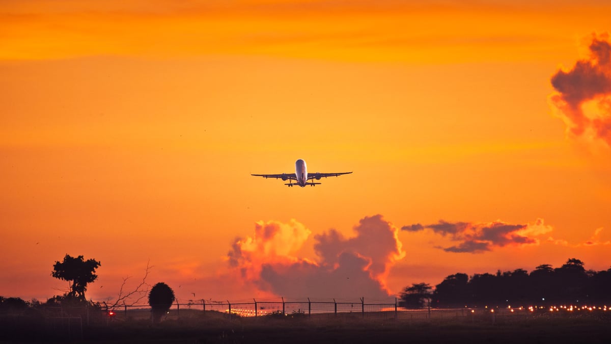 Commercial airliner ascending into vibrant sunset sky